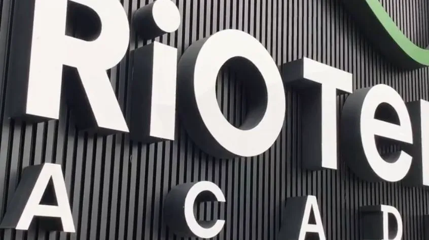 Letreiro tridimensional da Rio Tennis Academy sobre parede ripada preta
