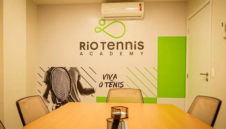 Sala de reunião com o logotipo e a assinatura Viva o tênis na parede