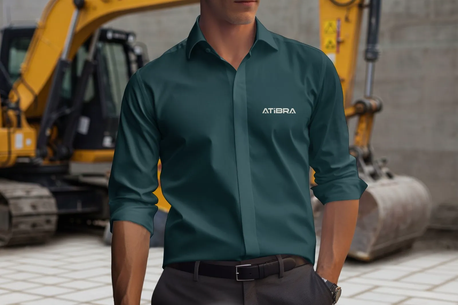 Atibra Homem de camisa social verde petróleo com o logotipo Atibra diante de uma escavadeira