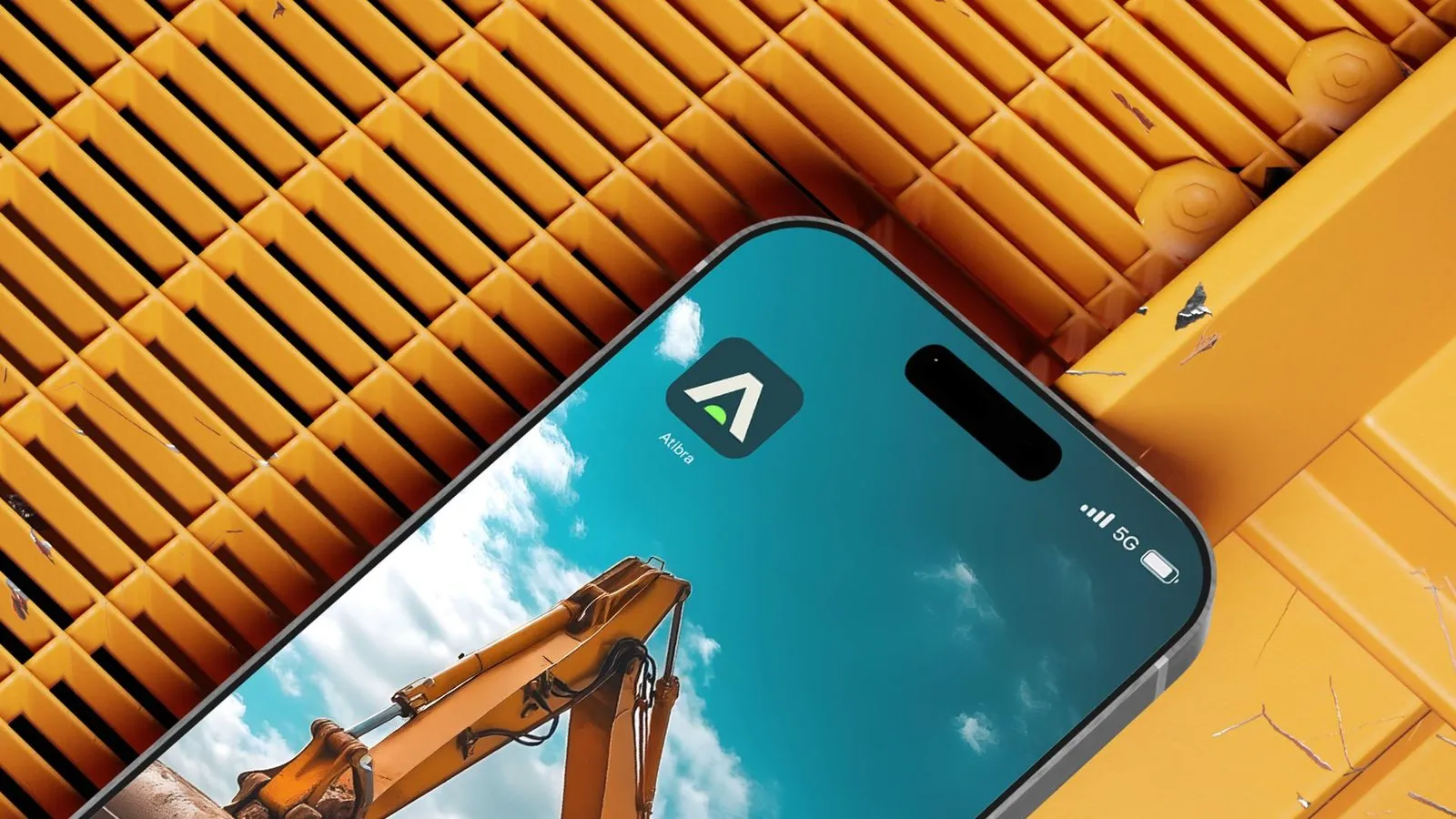 Atibra Celular com o ícone da Atibra apoiado sobre a grade de uma máquina amarela
