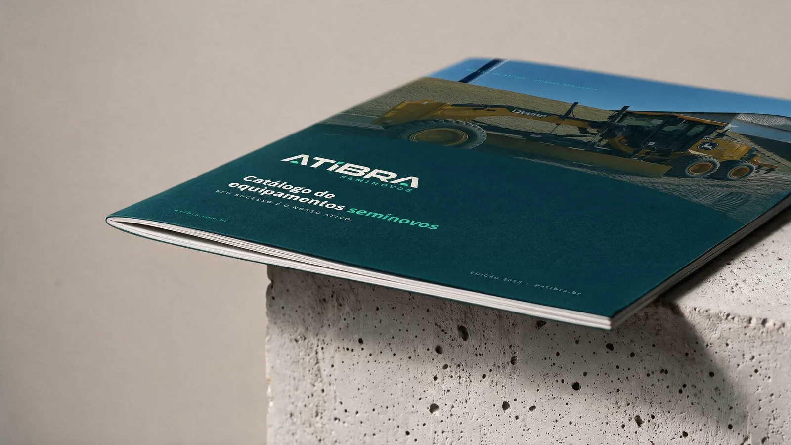 Atibra Mockup do catálogo de Seminovos impresso, fechado sobre um bloco de concreto, com a capa da Atibra