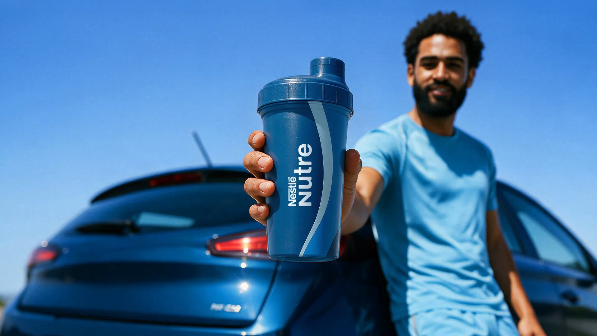 Nestlé Nutre Homem segurando um copo shaker azul-marinho com o logotipo Nestlé Nutre